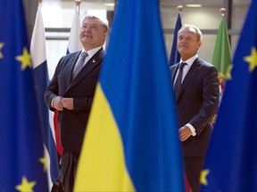 Ukrainian President Petro Poroshenko, left, and European Council President Donald Tusk walk between the EU and Ukrainian flags during arrivals at the Europa building in Brussels on Thursday, June 22, 2017. Ukrainian President Petro Poroshenko is meeting European Council President Donald Tusk on the sidelines of an EU summit. (AP Photo/Virginia Mayo)