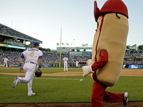 Kansas City Royals players take to the field while a contestant in a hot dog race runs along the warning track before the sixth inning of the team's baseball game against the Toronto Blue Jays on Friday, June 23, 2017, in Kansas City, Mo. (AP Photo/Charlie Riedel)