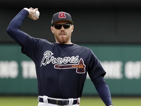FILE - In this Tuesday, Feb. 21, 2017 file photo, Atlanta Braves first baseman Freddie Freeman warms up during a spring training baseball workout in Kissimmee, Fla. Freddie Freeman plans to move from first base to third base to keep Matt Adams' bat in the Braves' lineup. Freeman took grounders at third base before batting practice early Wednesday, June 21, 2017  and also made throws to first base.(AP Photo/John Raoux, File)
