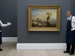 Members of staff at Sotheby's auction house wait next to an oil painting entitled ' Ehrenbreitstein' (1835), by British artist J.M.W.Turner, in London, Friday, June 30, 2017. The painting is expected to be sold for some 15-25 million pounds, (US$18.7-31.2 million, euro 17.3-28.9 million) when sold at auction on July 5. (AP Photo/Alastair Grant)