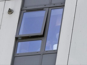 A woman speaks on the phone behind her flat window of Bray Tower, part of the Chalcots Estate in the borough of Camden, in London, Monday, June 26, 2017. The apartments were evacuated after fire inspectors concluded that the buildings were unsafe because of problematic fire doors, gas pipe insulation, and external cladding similar to that blamed for the rapid spread of a fire that engulfed Grenfell Tower on June 14. (AP Photo/Frank Augstein)