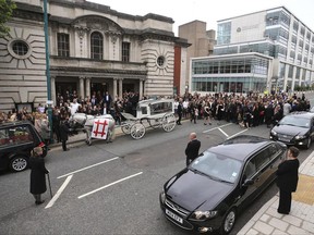 The coffin of Martyn Hett, who was killed in the Manchester Arena bombing, leaves Stockport Town Hall Plaza following his funeral service, in Stockport, England, Friday June 30, 2017. Mariah Carey sent a video message and stars of the British TV show "Coronation Street" were among the mourners at a funeral for Manchester concert bombing victim Martyn Hett. Hett was one of 22 people killed when a suicide bomber struck concertgoers leaving an Ariana Grande show in the northwest England city on May 22.  (Peter Byrne/PA via AP)