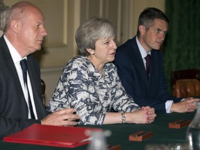 Britain's Prime Minister Theresa May, centre, sits with First Secretary of State Damian Green, left, and Government Chief Whip Gavin Williamson during their meeting with the Democratic Unionist Party (DUP) leader Arlene Foster, DUP Deputy Leader Nigel Dodds, and DUP MP Jeffrey Donaldson inside 10 Downing Street in central London, Monday June 26, 2017. The two parties struck a deal at the meeting.