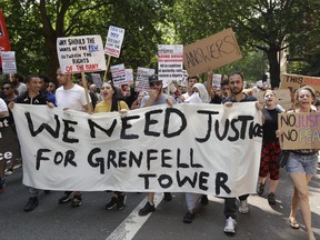 Demonstrators hold a banner demanding justice for the victims of the recent deadly apartment block fire at Grenfell Tower, as they march towards parliament in central London Wednesday June 21, 2017. The mass "Day of Rage" demonstration is timed to coincide with the state opening of parliament Wednesday. (AP Photo / Matt Dunham)