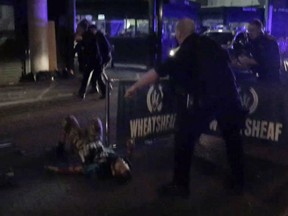 In this image made from video taken on Saturday, June 3, 2017, one of the suspects from the London Bridge attack, wearing what appear to be canisters strapped to his chest, lies on the ground after being shot by police