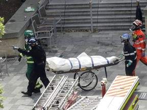 Emergency workers wheel away a body from the fire-gutted Grenfell Tower in London, Friday, June 16, 2017