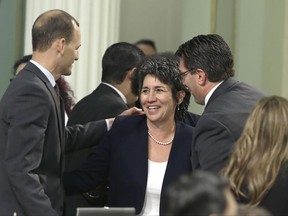 FILE - In this Sept. 9, 2015, file photo, assemblywoman Susan Talamantes Eggman, D-Stockton, is congratulated by assembly members Kevin McCarty, D-Sacramento, left, and Jay Obernolte, R-Big Bear Lake, after her right-to die measure was approved by the state Assembly in Sacramento, Calif. California health officials reported Tuesday, June 27, 2017, that 111 terminally ill people took drugs to end their lives in the first six months after a 2016 law made the option legal in the nation's most populous state. (AP Photo/Rich Pedroncelli, File)