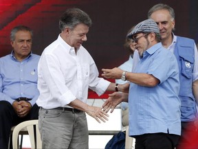 Colombia's President Juan Manuel Santos, left, shakes hands with Rodrigo Londono, also known as Timochenko or Timoleón Jiménez, right, the top commander of the Revolutionary Armed Forces of Colombia, FARC, during an act to commemorate the completion of the disarmament process in Buenavista, Colombia, Tuesday, June, 27, 2017. The United Nations says it has concluded the disarmament process for individual arms as part of a peace deal between FARC rebels and the government. (AP Photo/Fernando Vergara)