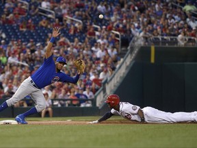 The ball flies past Chicago Cubs third baseman Jeimer Candelario, left, as Washington Nationals' Michael Taylor, right, steals third during the fourth inning of a baseball game, Tuesday, June 27, 2017, in Washington. Taylor went on to score on the play. Chicago Cubs catcher Miguel Montero was charged with a throwing error on the play.(AP Photo/Nick Wass)