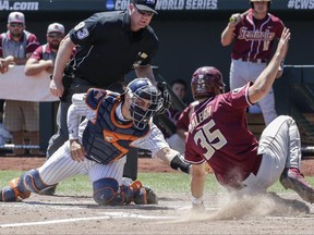 Cal State Fullerton catcher Chris Hudgins (24) tags out Florida State's Cal Raleigh in the fourth inning of an NCAA College World Series baseball game in Omaha, Neb., Monday, June 19, 2017. (AP Photo/Nati Harnik)