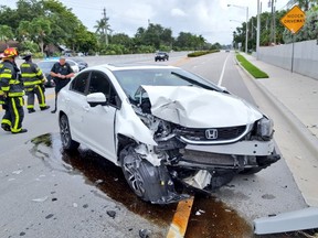 A white car hit a light pole, knocking it into the street in Cooper City, which is northwest of Miami.