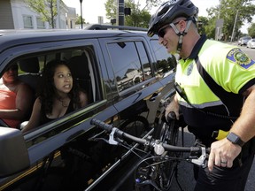 FILE- In this July 20, 2016 file photo, police officer Matthew Monteiro speaks to a motorist about texting while driving while patrolling on his bicycle in West Bridgewater, Mass. Drivers in Massachusetts would have to put down their phones under legislation to be taken up in the Senate on Thursday, June 29, 2017. The bill, designed to crack down on distracted driving, would prohibit cellphone use unless in hands-free mode. (AP Photo/Steven Senne, File)