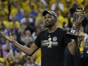 Golden State Warriors' Kevin Durant holds up the Bill Russell Trophy as playoff MVP in the wake of their 129-120 win over the Cleveland Cavaliers in Game 5 of the NBA Finals Monday night in Oakland. Durant led the way with 39 points as the Warriors completed the NBA series win in five games.