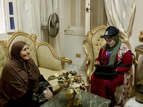 In this May 24, 2017 photo, a Central Agency for Public Mobilization and Statistics worker looks at the identification card of an elderly woman as she fills them into the tablet at her home, in the Omraniyah district of Cairo, Egypt. Census workers going door to door in Egypt's teeming neighborhoods and crowded towns are discovering a new country _ of more than 20 million people born in the last decade alone. (AP Photo/Nariman El-Mofty)