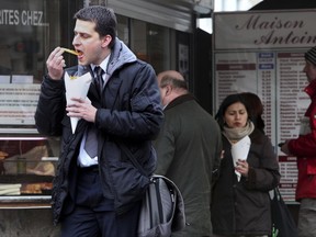 FILE - In this Feb. 4, 2010, file photo, a man eats Belgian fries at a frites stand in Brussels. A regional Belgian minister recently alarmed the nation with warnings that the EU would force fries to be blanched before they hit the fat to remove cancer-causing elements. The EU on Tuesday, June 20, 2017 reported that it had no intention whatsoever of banning Belgian fries. (AP Photo/Geert Vanden Wijngaert, File)