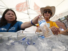 Salvation Army volunteers Evangeline Ford, left, and Jackie Rifkin, right, restock a cooler with bottles of water at a hydration station for people as they try to keep hydrated and stay cool as temperatures climb to near-record highs, Monday, June 19, 2017, in Phoenix. (AP Photo/Ross D. Franklin)