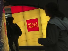FILE - In this Thursday, Oct. 13, 2016, file photo, commuters walk by a Wells Fargo ATM location at New York's Penn Station. On Wednesday, June 28, 2017, the Federal Reserve gave the green light to all 34 of the biggest banks in the U.S. to raise their dividends and buy back shares, judging their financial foundations sturdy enough to withstand a major economic downturn. Those allowed to raise dividends or repurchase shares include the four biggest U.S. banks: JPMorgan Chase, Bank of America, Citigroup and Wells Fargo. (AP Photo/Swayne B. Hall, File)