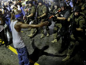 FILE - In this Aug. 20, 2014, file photo, Police arrest a man as they disperse a protest in Ferguson, Mo., following the shooting of unarmed 18-year-old Michael Brown in the St. Louis suburb on Aug. 9. Attorneys for the U.S. Department of Justice say Ferguson, Missouri, is making progress in the effort to end racial bias in police and court practices, but more transparency is needed. U.S. District Judge Catherine Perry on Thursday, June 22, 2017, heard an update on a consent agreement reached in 2016.(AP Photo/Charlie Riedel, File)