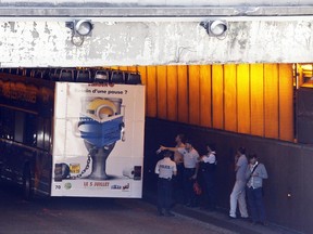 French police officers work by a bus that hit the roof of a Paris tunnel, Friday, June 23, 2017 . A tour bus company says one of its double-decker, open-roof buses hit the roof of a Paris tunnel, injuring four people, one of them seriously. (AP Photo/Thibault Camus)