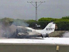 Flame and smoke erupt from a twin-engine prop jet after it crashed on Interstate 405, just short of the runway at John Wayne Orange County Airport, rear, in Costa Mesa, Calif., Friday, June 30, 2017. Officials said two people were injured and were taken by helicopter to a hospital. The freeway was shut down in both directions. (Wendy Haskell via AP)