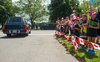 A group of school children wave flags to the hearse following the funeral for Nazzareno Tassone in his hometown of Niagara Falls, Ont., June 21, 2017.