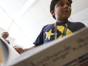 In this Wednesday, June 14, 2017, photo, Ezequiel Banegas, a sixth grader, reads from his story in "Luchando por un Mejor Futuro" (Fighting for a better future) in Brentwood, N.Y. The book is a collection of stories about the students making the journey to the United States while attempting to escape violence. In the book the children mention seeing their parents beaten or murdered, hiding from authorities and being shot. (AP Photo/Michael Noble Jr.)