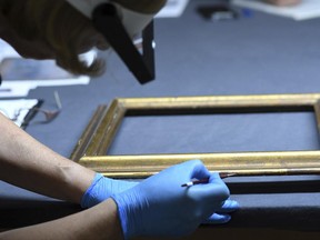 An employee works on a frame during a press talk on the preparations of an exhibition of exemplary works from the Gurlitt found, an art collection of Cornelius Gurlitt discovered in 2012, in November in Bonn, Germany,  Tuesday June, 27, 2017. (Henning Kaiser/dpa via AP)