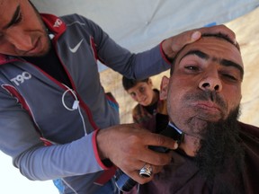 A displaced Iraqi man has his beard shaved at the Hammam al-Alil camp for internally displaced people south of Mosul, on May 25, 2017.