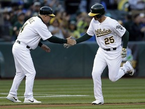 Ryon Healy, right, of the Oakland A's is congratulated by coach Chip Hale after hitting his second homer of the night in MLB action Monday against the Toronto Blue Jays in Oakland. Healy had all five RBI as the A's posted a 5-3 victory, denying the Jays a chance to reach the .500 mark on the season.