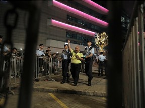 A pro-democracy activist is arrested by police officers after he climbed up to a giant flower statue bequeathed by Beijing in 1997 in Golden Bauhinia Square of Hong Kong Wednesday, June 28, 2017.  Hong Kong is planning a big party as it marks 20-years under Chinese rule, ceded from British rule. (AP Photo/Vincent Yu)
