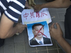 Pro-democracy activists paste the words "Chinese Communist Demon Claws" on a defaced photo of Chinese President Xi Jinping before attempting to march in protest towards the venue where official ceremonies are held to mark the 20th anniversary of Chinese rule over Hong Kong in Hong Kong, Saturday, July 1, 2017. Chinese President Xi Jinping's three-day visit aimed at stirring Chinese patriotism in the former British colony people has promoted a massive police presence. (AP Photo/Ng Han Guan)