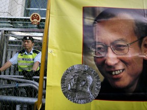 FILE - In this Dec. 5, 2010 file photo, a police officer stands guard beside a picture of jailed Chinese dissident Liu Xiaobo outside the Chinese government liaison office in Hong Kong. Jailed Chinese Nobel peace laureate Liu has been released on medical parole after being diagnosed with late-stage liver cancer, his lawyer said Monday, June 26, 2017. (AP Photo/Kin Cheung, File)