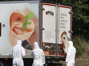 FILE - In this Thursday, Aug. 27, 2015 file photo, investigators stand near an abandoned truck on the shoulder of Highway A4 near Parndorf, Austria, south of Vienna. Officials said they discovered 71 badly decomposed bodies of men, women and children, inside and that some may never be identified.  The  trial of 11 alleged human smugglers indicted for the deaths of 71 migrants who suffocated in the back of a refrigerated truck in 2015 starts in Kecskemet, Hungary, Wednesday June 21, 2017.  (AP Photo/Ronald Zak,file)