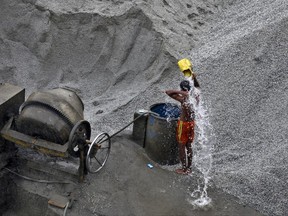 A laborer takes bath after the day's work at a site where he makes cement blocks used for construction, in Bangalore, India, Saturday, June 24, 2017. There is no direct supply of potable water at homes in most of the poor neighborhoods in the country. (AP Photo/Aijaz Rahi)