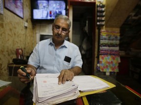 In this June 15, 2017 photo, Sanjiv Mehra, a toy shop owner checks his ledger at his shop in Khan Market, New Delhi, India. Indian businesses are in a tizzy trying to comply with a long-awaited reform in the country's sales regime. The government says the Goods and Services Tax going into effect July 1 will boost the economy by streamlining business within a single market. Traders and business owners are still trying to figure out how it will work. (AP Photo/Altaf Qadri)