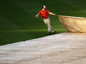 Sunlight shines on a groundskeeper as he helps to remove a tarp from the field during a rain delay before a baseball game between the Baltimore Orioles and the Cleveland Indians in Baltimore, Wednesday, June 21, 2017. (AP Photo/Patrick Semansky)