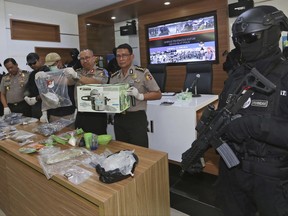 National police spokesman Maj. Gen. Setyo Wasisto, center, shows a pressure cooker and other evidence confiscated from suspected militants during a press conference in Jakarta, Indonesia, Thursday, June 22, 2017. Indonesian police say they have arrested 41 suspected militants following last month's twin suicide bombings in the capital that killed three policemen. (AP Photo/Tatan Syuflana)