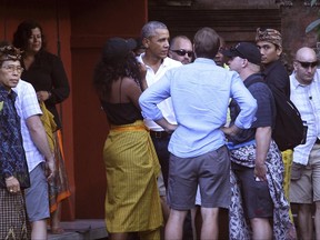 Former U.S. President Barack Obama, center, his wife Michelle, center front, talk to his staffs during they visit at Tirta Empul temple in Bali island, Indonesia, Tuesday, June 27, 2017. Obama and his family arrived last week on the resort island for a vacation in the country where he lived for several years as a child. (AP Photo/Firdia Lisnawati)