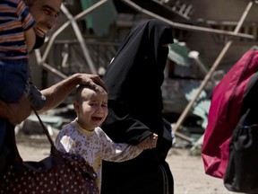 FILE - In this May 17, 2017 file photo, a girl with a shaved head and her father cry as the family flees the al-Rifai neighborhood while Iraqi special forces battle Islamic State militants in western Mosul, Iraq. In a report Thursday, June 22, the United Nation children's agency said they documented a number of cases of Islamic State group fighters killing the children of families trying to flee militant-held neighborhoods in Mosul. (AP Photo/Maya Alleruzzo, File)