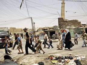 FILE - In this Monday, June 8, 2009 file photo, residents walk past the crooked minaret in a busy market area in Mosul, Iraq. Iraq's ministry of defense says Islamic State militants destroyed the al-Nuri mosque in Mosul and the adjacent iconic leaning minaret when fighters detonated explosives inside the structures late Wednesday night on June 21, 2017. (AP Photo/Maya Alleruzzo, File)