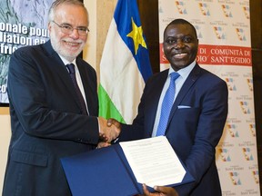 Foreign Minister of the Central African Republic Charles Armel Doubane, right, and Sant'Egidio Community founder Andrea Riccardi congratulate each other as they hold the just signed copy of the Political Agreement for Peace in the Central African Republic at the Sant'Egidio headquarters in Rome, Monday, June 19, 2017. Members of 13 Central African Republic's militant groups signed a preliminary agreement to stop the civil war, reaffirm the unity of the country, and the respect of human and civil rights. (AP Photo/Domenico Stinellis)
