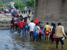 In this Monday, June 26, 2017 photo, migrants cross the Roja river near the northern Italian town of Ventimiglia, as they try to reach the French border. The aid group Doctors Without Borders (MSF) said Tuesday, June 27, 2017, that about 100 migrants, including unaccompanied minors, had been sleeping for weeks near the river bank by the Italian border town. (Chiara Carenini/ANSA via AP)
