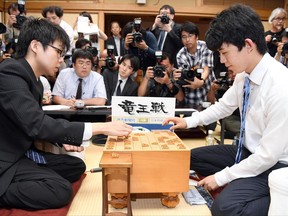 In this Monday, June 26, 2017 photo, Sota Fujii, right, replays a move against Yasuhiro Masuda in front of media after Fujii defeated Masuda to break a 30-year-old record with his 29th win in a row, in the qualifying round of a major tournament in Tokyo. The 14-year-old boy is taking his country by storm with a record-breaking debut in Japanese chess. (Muneyoshi Someya/Kyodo News via AP)