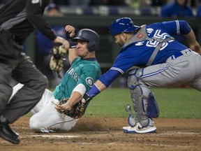 Danny Valencia of the Seattle Mariners is tagged out at the plate by Toronto Blue Jays' catcher Russell Martin during MLB action Friday in Seattle. The Mariners were 4-2 winners.