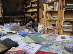 In this Thursday, June 15, 2017 photo, Hamzeh AlMaaytah sorts books at his Mahall al-Maa bookstore, in Jordan's capital, Amman. AlMaaytah has nurtured a community of book lovers, keeping his bookstore in Amman's old center open around the clock, encouraging customers to linger over rare treasures and often allowing them to set the price for a purchase. His supporters recently had a chance to repay him when the local landmark was threatened with closure: by April, 330 people from more than 20 countries had contributed $18,000 in a crowd-funding campaign. (AP Photo/Reem Saad)