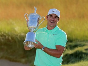 American Brooks Koepka holds up the championship trophy after winning the U.S. Open golf championship at the Erin Hills Golf Club in Erin, Wisc. on Sunday. Koepka tied a tournament scoring record by finishing 16-under to win his first major title.