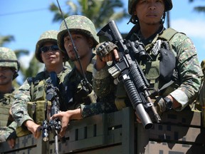 Philippine troops ride on their truck on their way to the frontline in the outskirts of Marawi on the southern island of Mindanao on June 28, 2017.  Islamist militants occupying parts of a southern Philippine city used a water route to bring in ammunition and evacuate wounded fighters, helping them withstand a five-week military offensive, the army said June 27