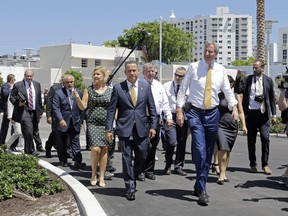 Miami Beach Mayor Philip Levine, foreground left, and New York City Mayor Bill de Blasio, foreground right, tour the area where the city has raised streets and installed pumps to combat rising tides, Friday, June 23, 2017, in Miami Beach, Fla. The U.S. Conference of Mayors opens its annual meeting Friday in Miami Beach. Mayors of cities with populations of 30,000 or more will discuss plans to reduce the nation's carbon footprint and protect immigrant families. (AP Photo/Alan Diaz)