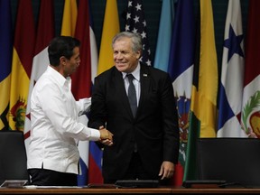 Mexico's President Enrique Pena Nieto, left, shakes hands with Luis Almagro, secretary general of the Organization of American States, during the opening of the 2017 OAS General Assembly in Cancun, Mexico, Monday, June 19, 2017. Venezuela's foreign minister walked out of a meeting of regional diplomats to discuss the South American country's political crisis on Monday as a 17-year-old anti-government demonstrator was shot and killed during clashes with security forces. The OAS meeting once again narrowly failed to approve a resolution that would have pushed back against some of Venezuelan President Nicolas Maduro's most radical actions. (AP Photo/Israel Leal)