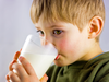 A young boy drinks a glass of milk.